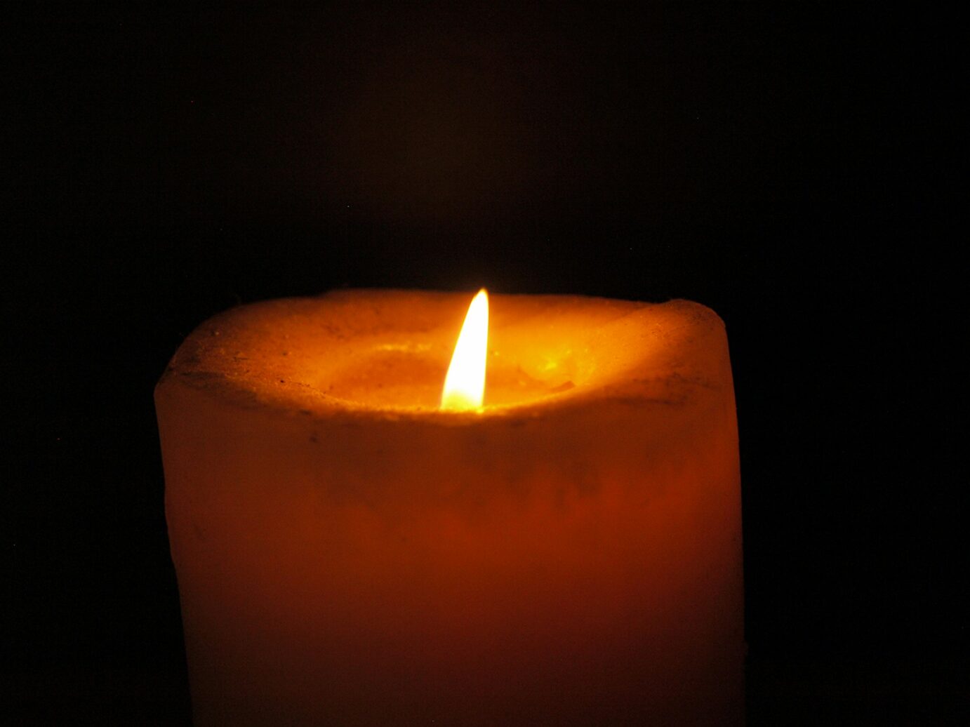 a lit candle burning in a dark room