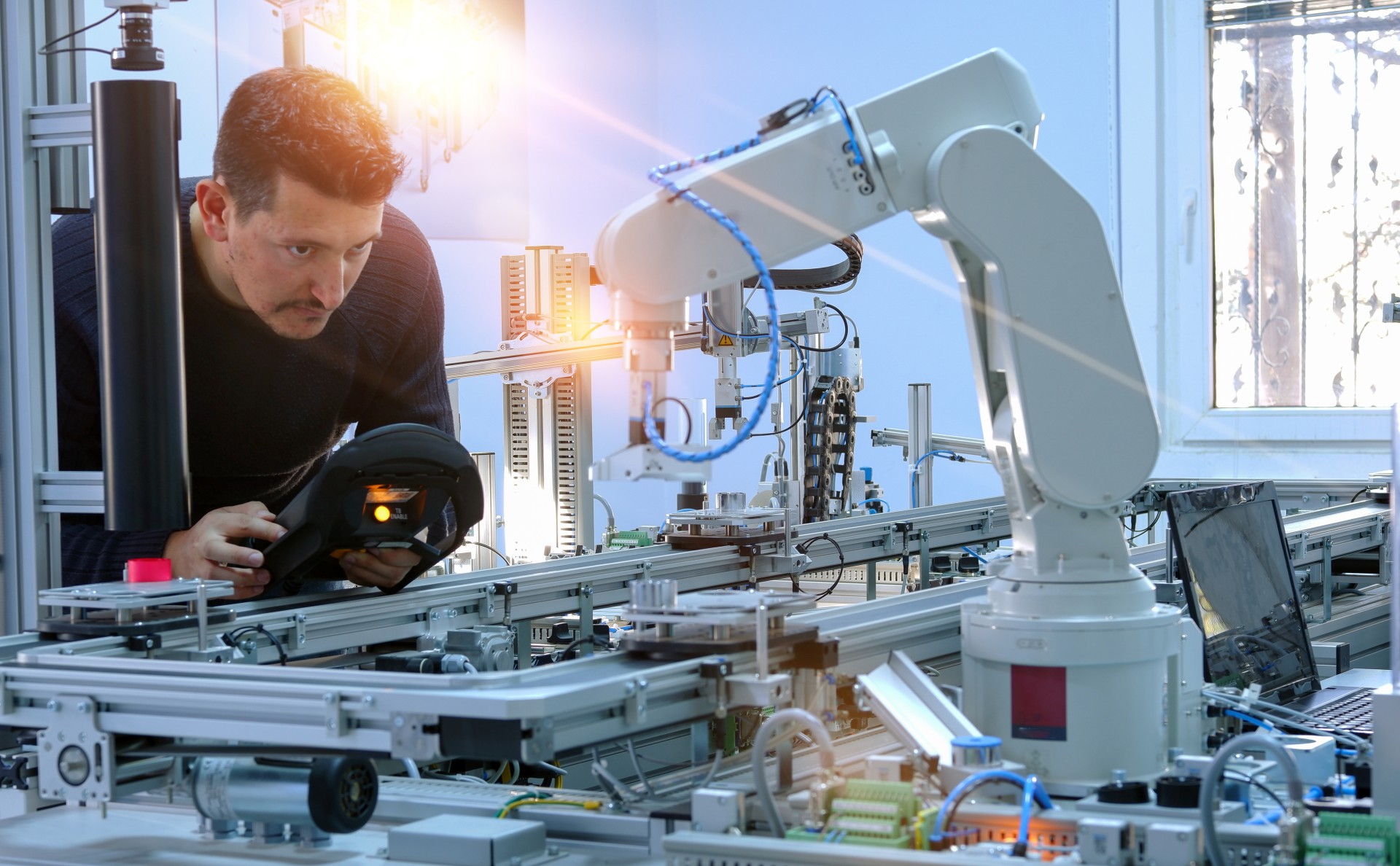 smart factory robotic arm man programming a robotic arm to use in a smart factory for industry 4.0 or 5.0 use