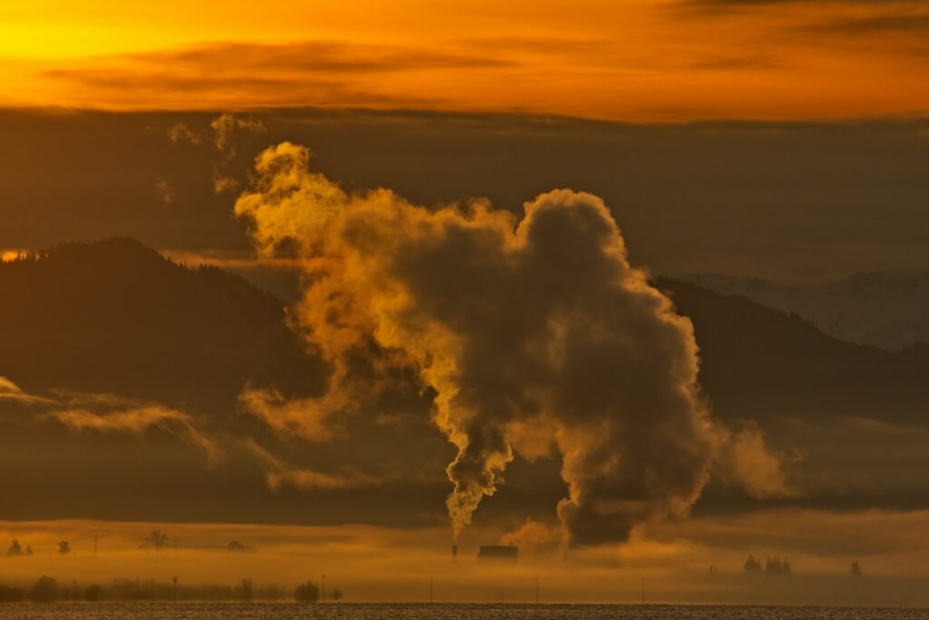 Hazy smokestack against a sunset sky