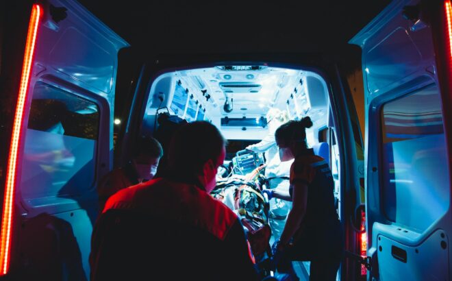 healthcare workers standing near an ambulance at night