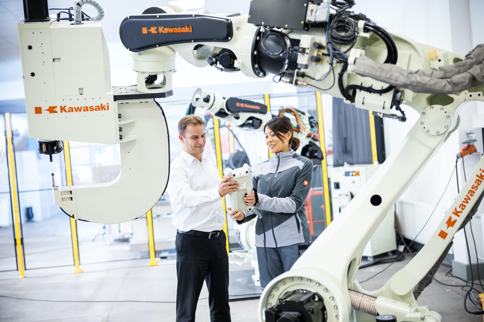 A robotics technician and a business man looking at an AI robot