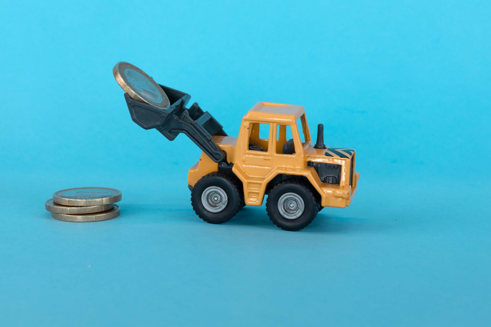 image of a toy truck with a front loader attached lifting coins