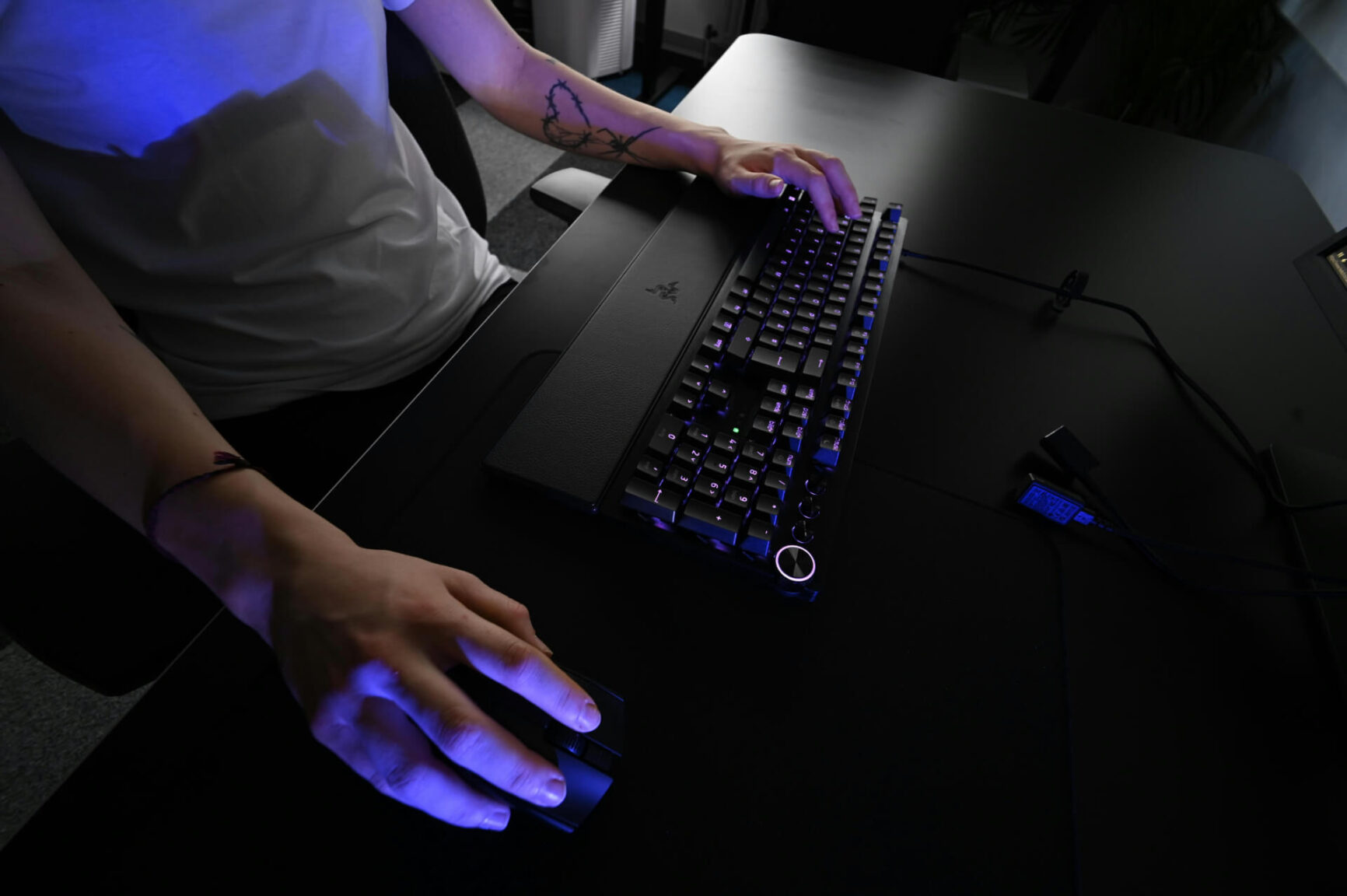 close up of someone's hands on a mouse and keyboard with blue light