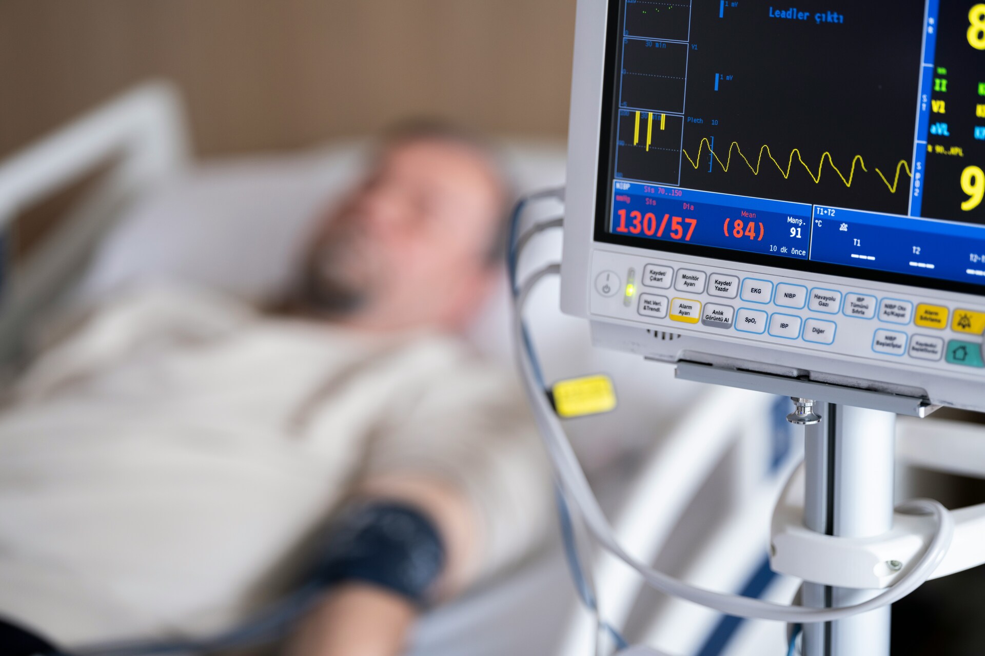 man in a hospital bed beside a monitor