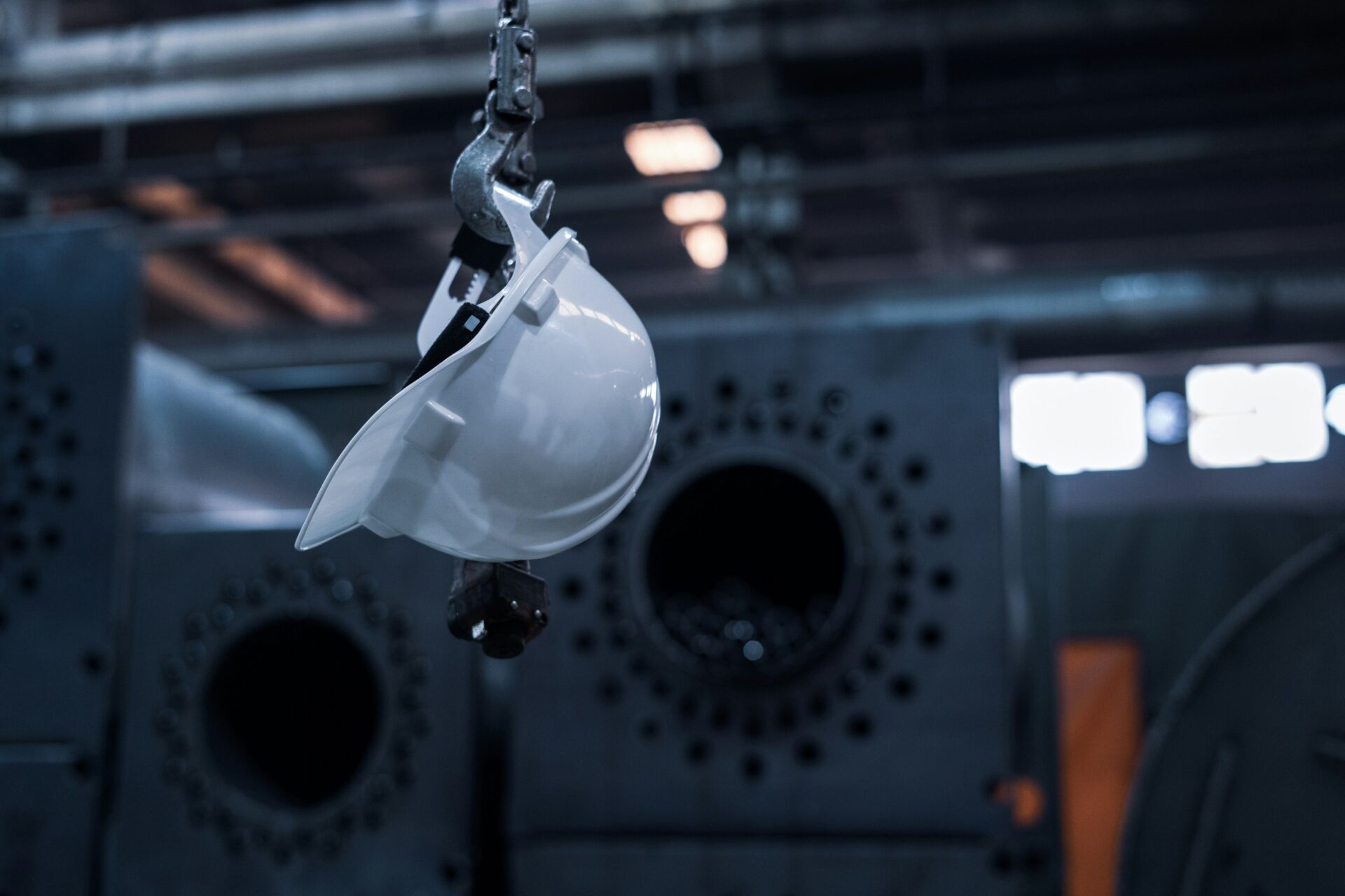 white hard hat hanging on a hook in an industrial environment